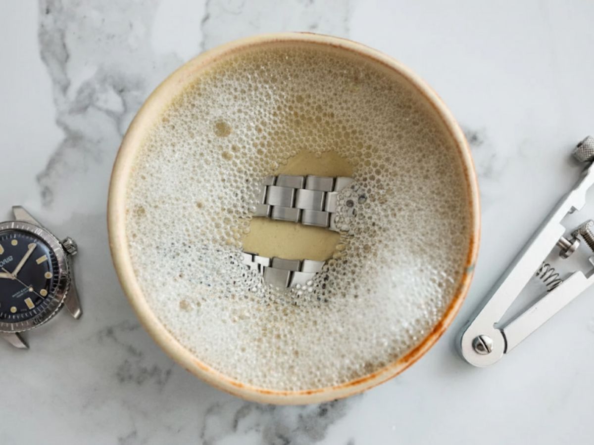 Ngâm dây đồng hồ kim loại đã tháo rời vào dung dịch khoảng 5-10 phút để làm mềm vết bẩn