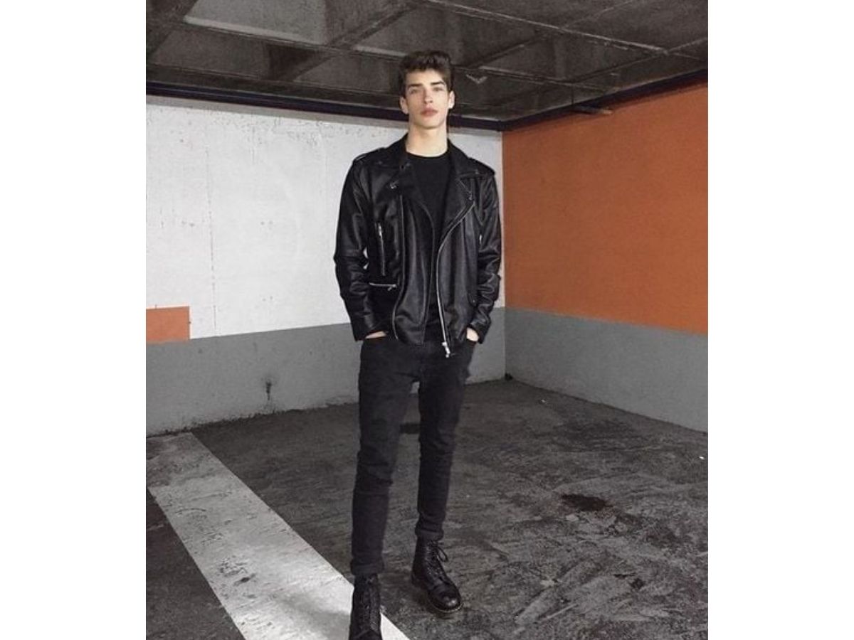 Người mẫu nam mặc áo racer da đen, áo thun đen, quần jeans đen và chelsea boots