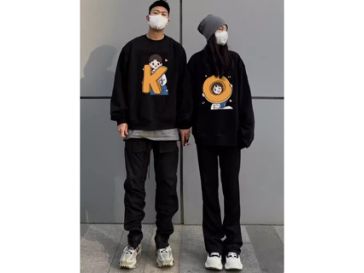 Cặp đôi nam nữ cùng mặc outfit áo sweater đen, quần jeans và sneaker, phong cách năng động