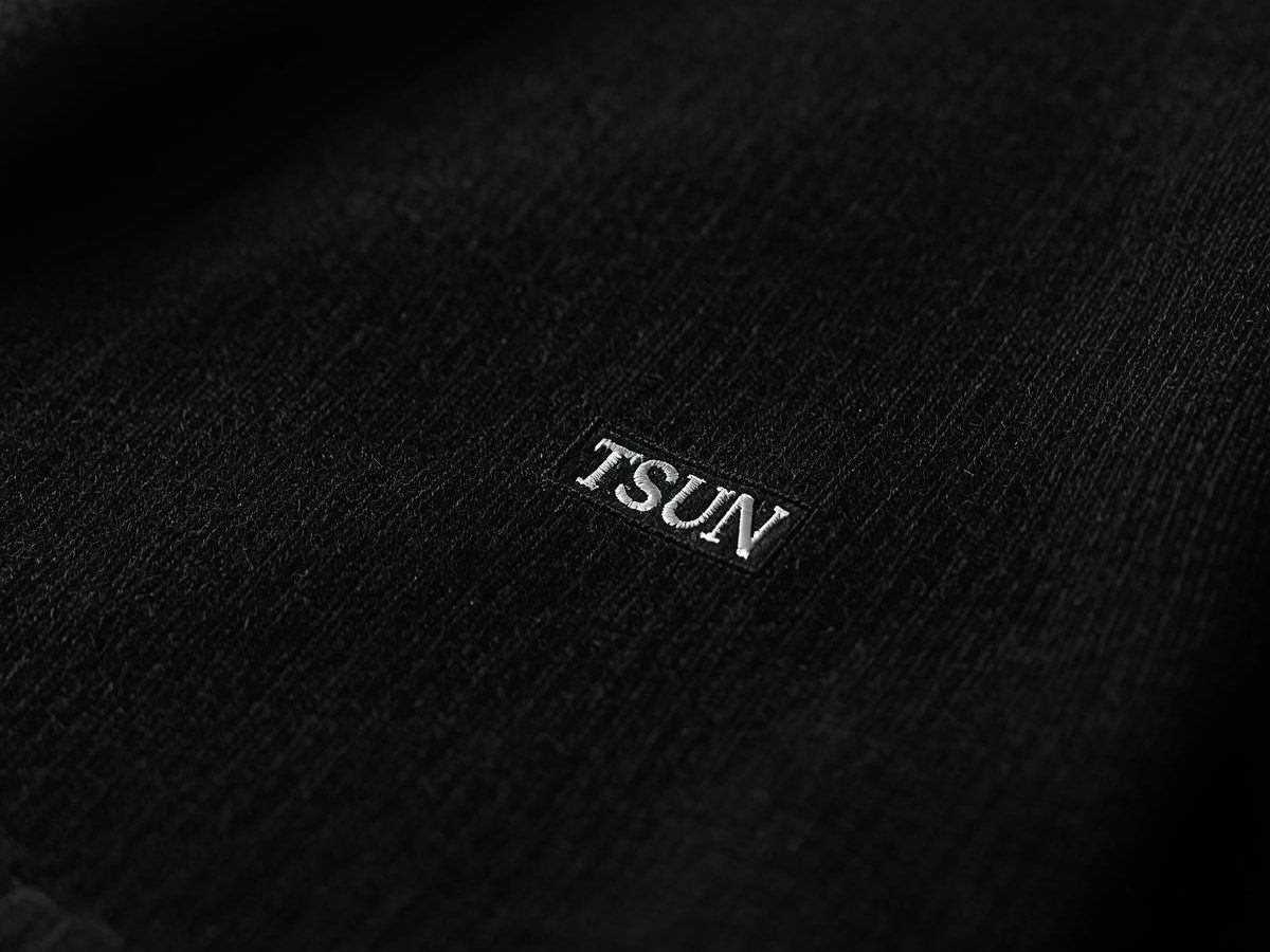 Chi tiết logo đồng xu của Dirty Coins trên ngực áo sweater đen