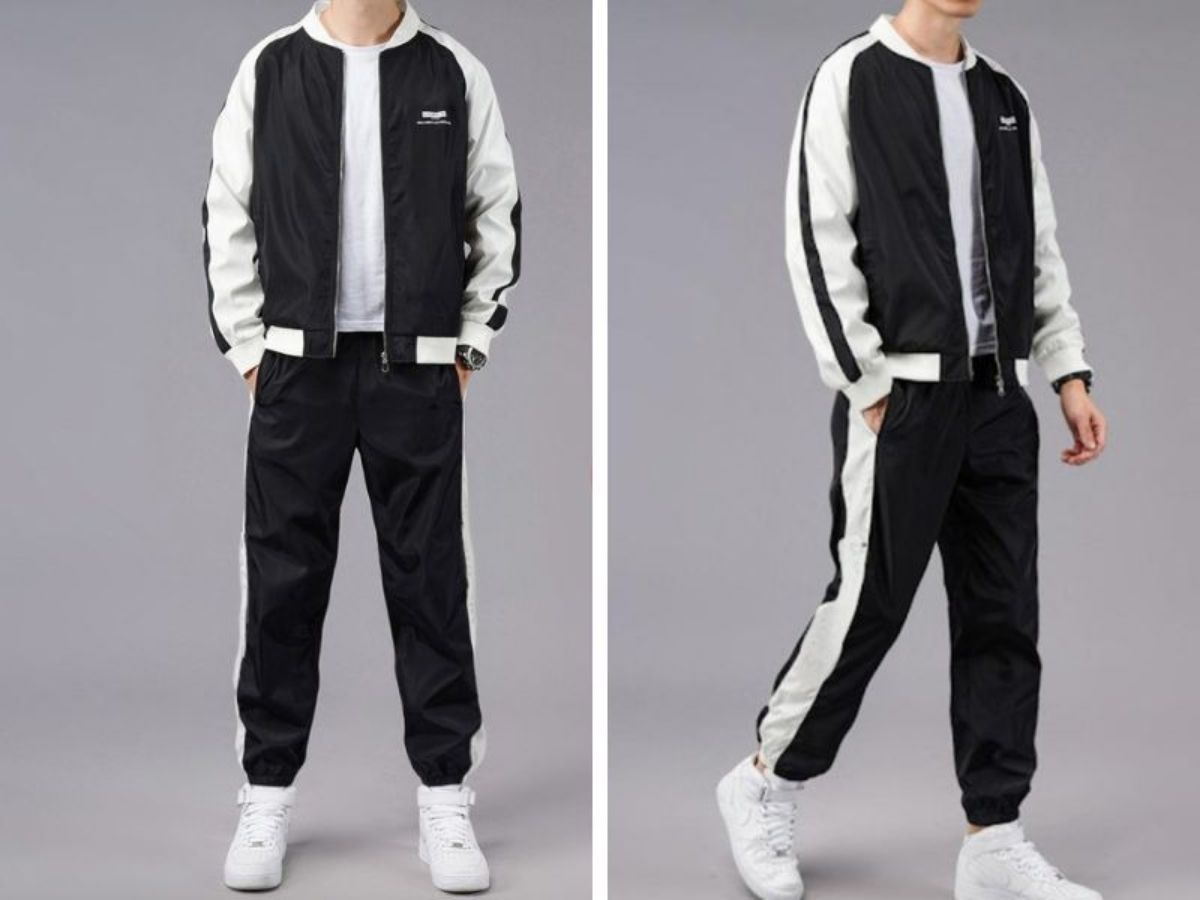 Người mẫu nam mặc set đồ gồm áo khoác dù phối màu, áo thun trắng, quần jogger đen và sneaker trắng