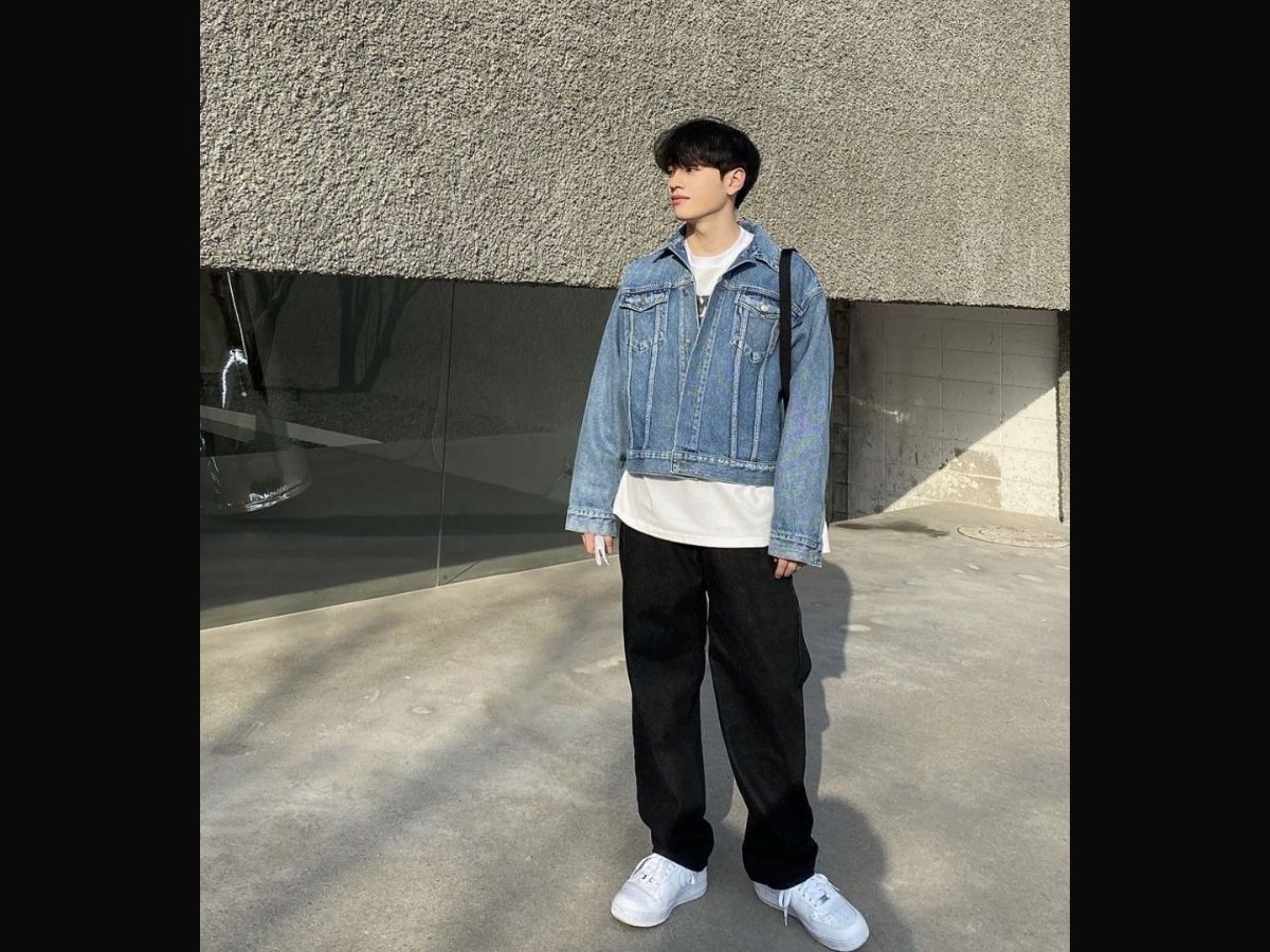 Chàng trai mặc áo khoác jeans xanh, áo thun trắng Coolmate, quần jeans đen và đi giày sneaker trắng