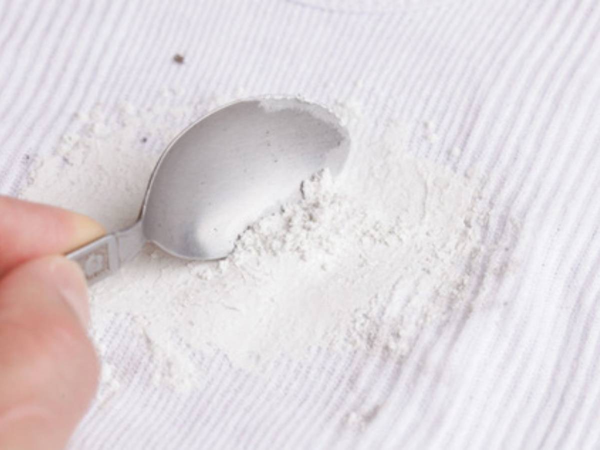 Cảnh một người dùng bột bắp rắc lên vết dầu mỡ trên thân áo nỉ