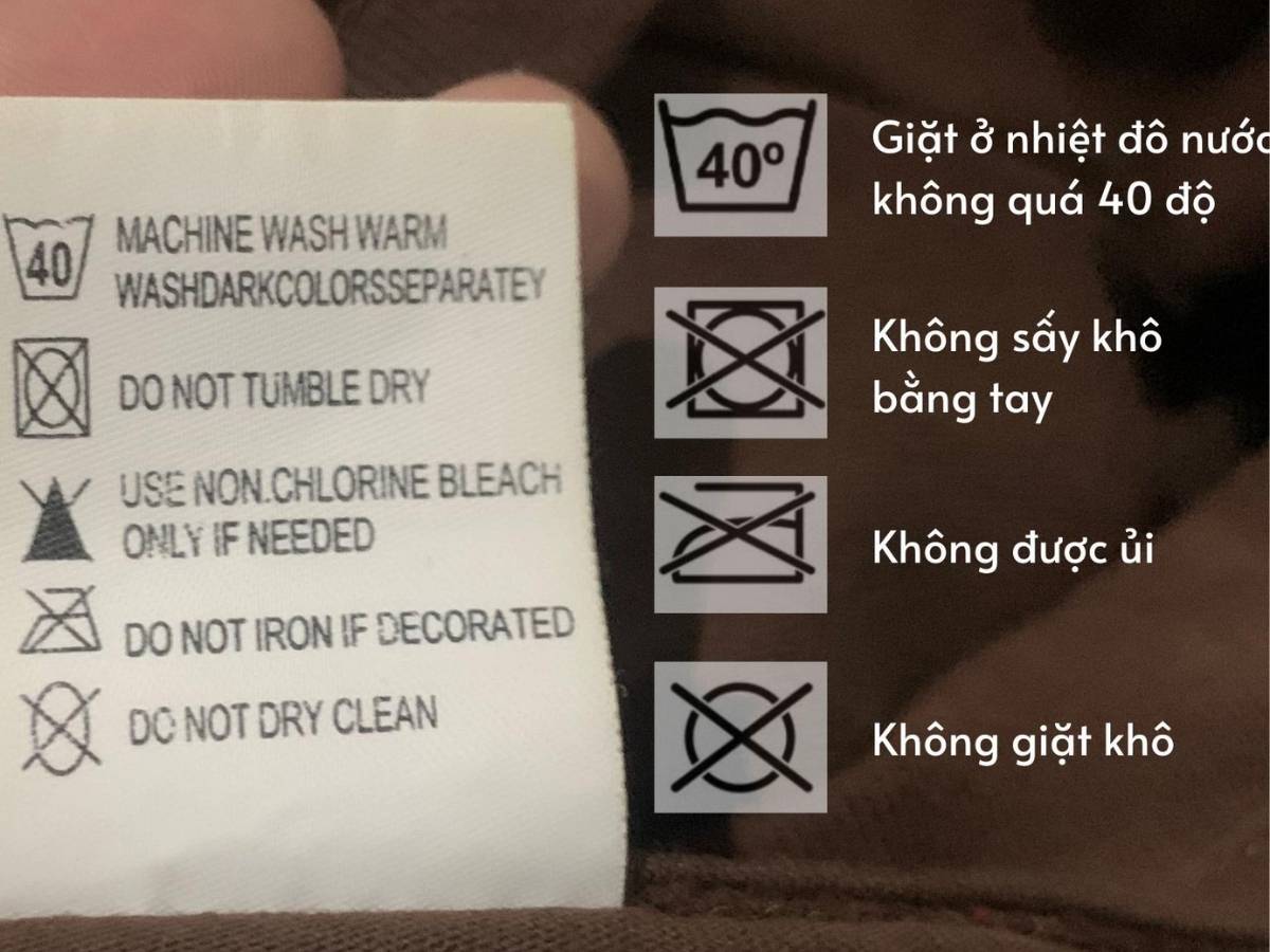 Cận cảnh nhãn mác của một chiếc áo khoác bóng chày các ký hiệu như "giặt tay", "không sấy nóng", "không tẩy"