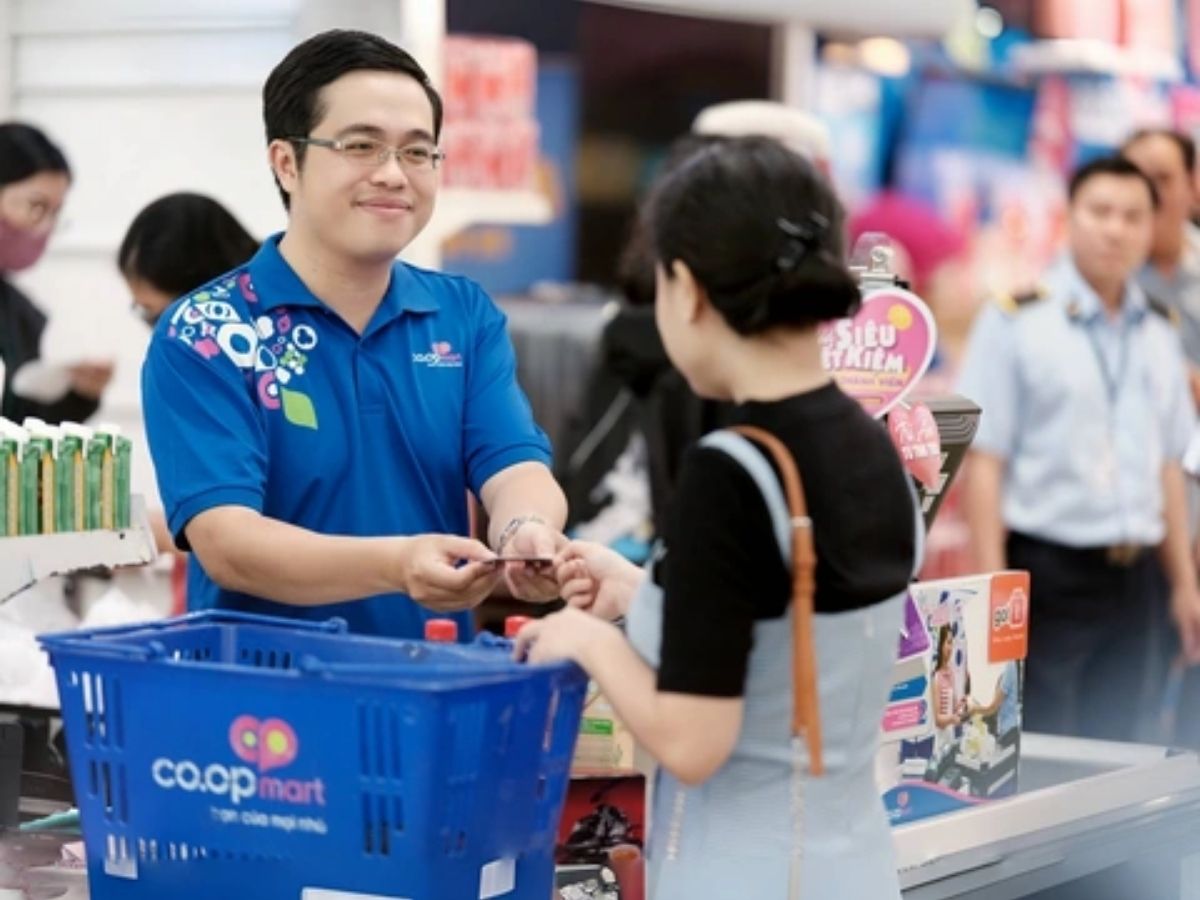 Nhân viên Coopmart mặc áo polo đồng phục màu xanh dương đang tư vấn cho khách hàng trong siêu thị