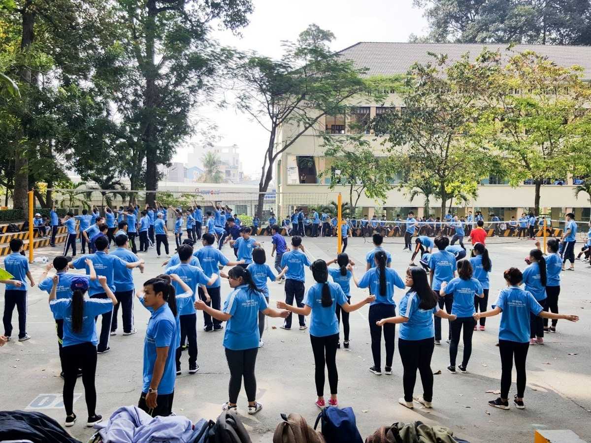 Sinh viên TDC đang chơi thể thao trong sân trường, mặc đồng phục áo polo xanh năng động